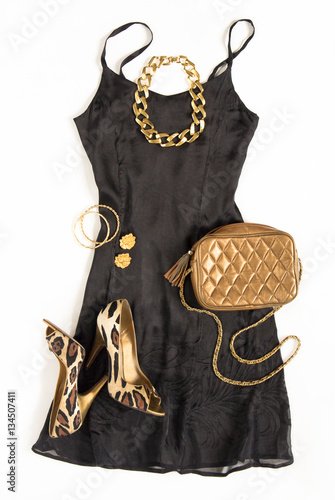 Christmas party outfit. Cocktail dress outfit, night out look on white background. Little black dress, gold bag, leopard shoes, gold necklace. Flat lay, top view