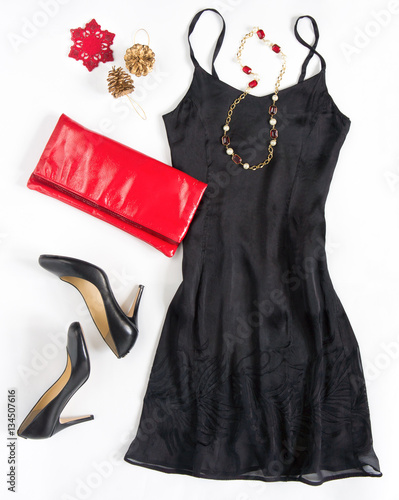 Christmas party outfi. Cocktail dress outfit, night out look on white background. Little black dress, red evening clutch , black shoes, red ang gold necklace. Flat lay, top view