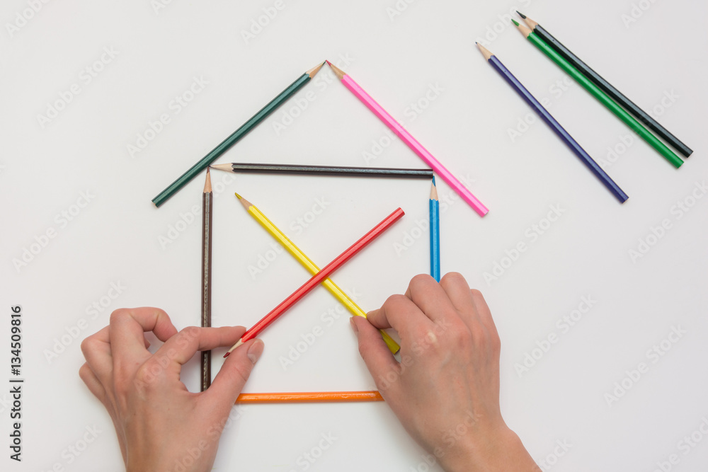 Women's hands are building a house from pencils Women's hands are building a house from pencils