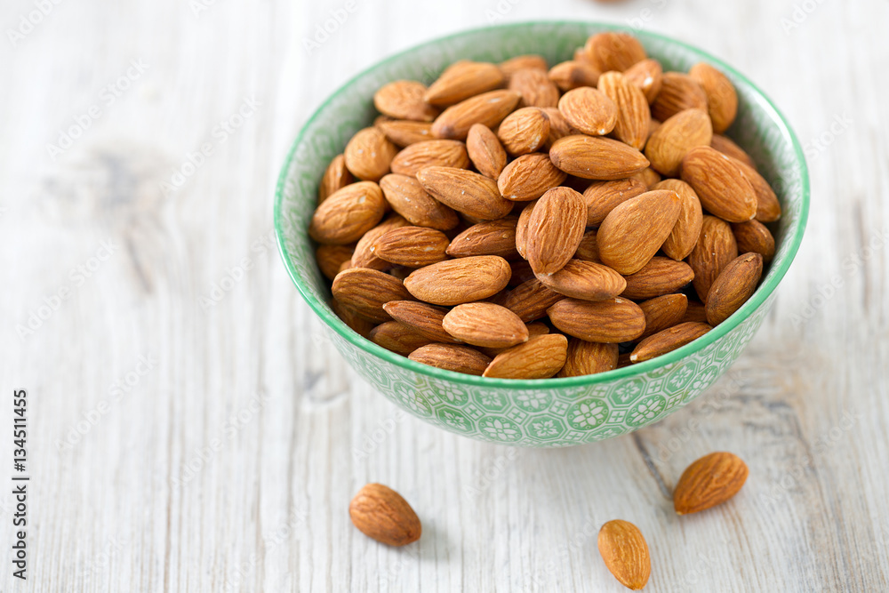 almonds in a bowl on wooden surface almonds in a bowl on wooden surface