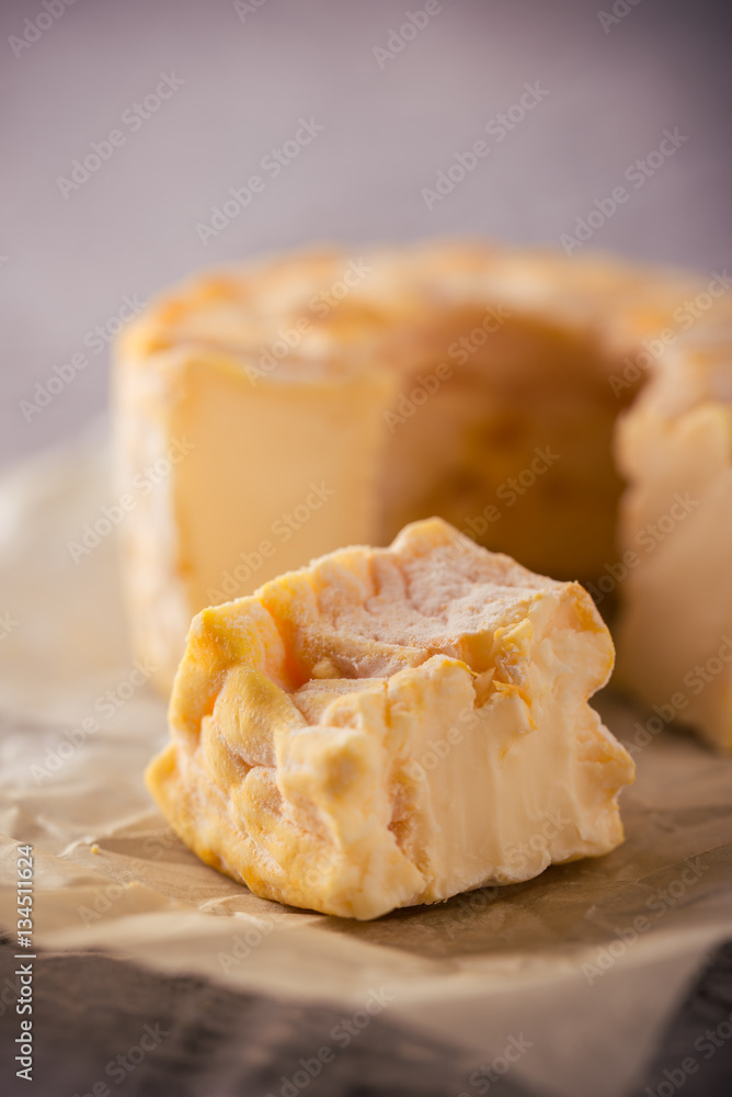 Portion cut from whole golden camembert cheese on grey board Portion cut from whole golden camembert cheese on grey board
