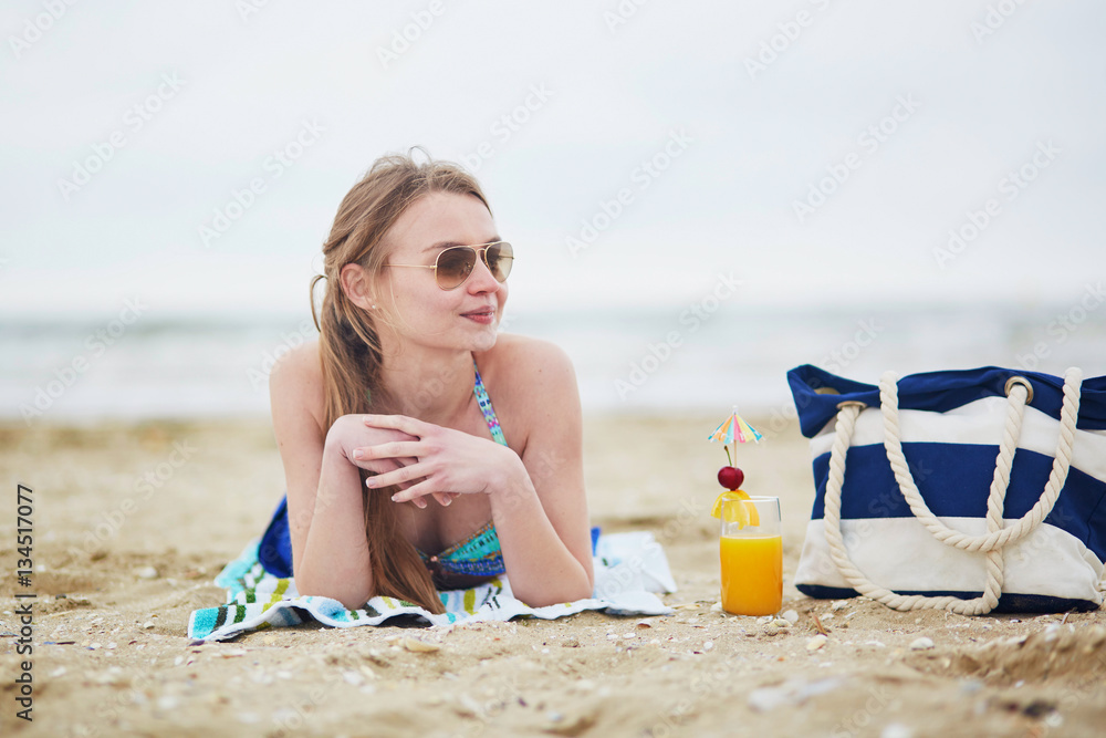Woman relaxing and sunbathing on beach - obrazy, fototapety, plakaty 