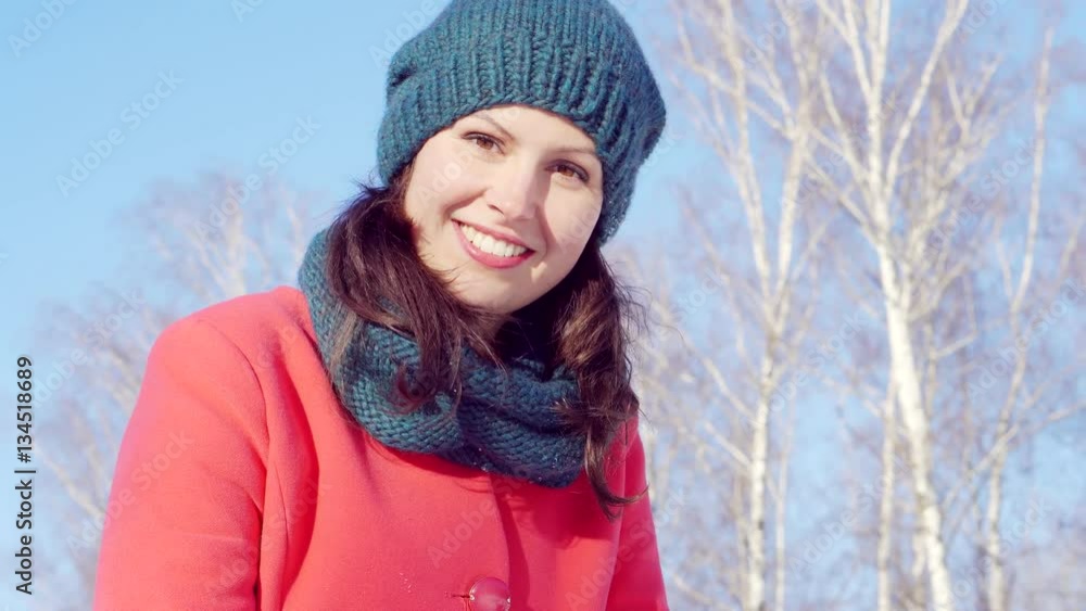 Beautiful young girl in a red coat in Sunny weather, standing on the street in the Park Beautiful young girl in a red coat in Sunny weather, standing on the street in the Park