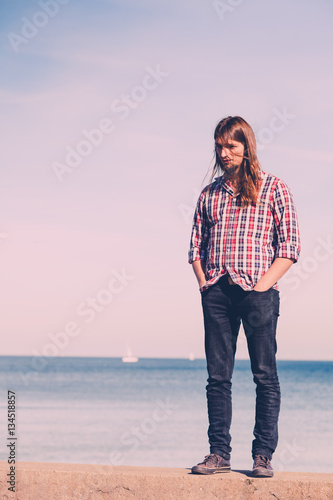 Man walking relaxed on stone wall by seaside © Voyagerix