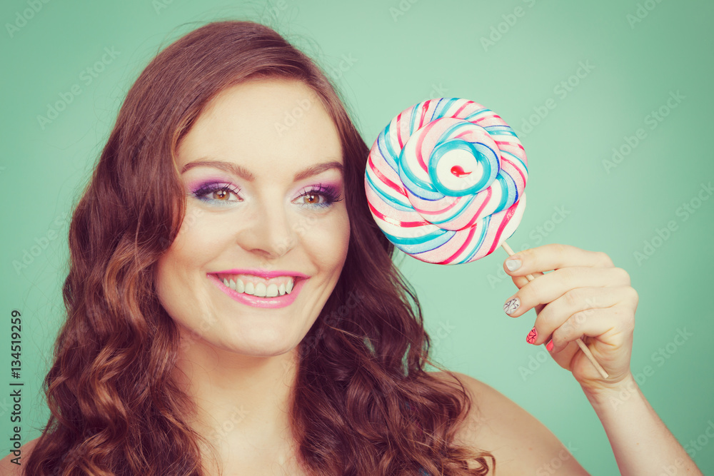 Smiling girl with lollipop candy on teal