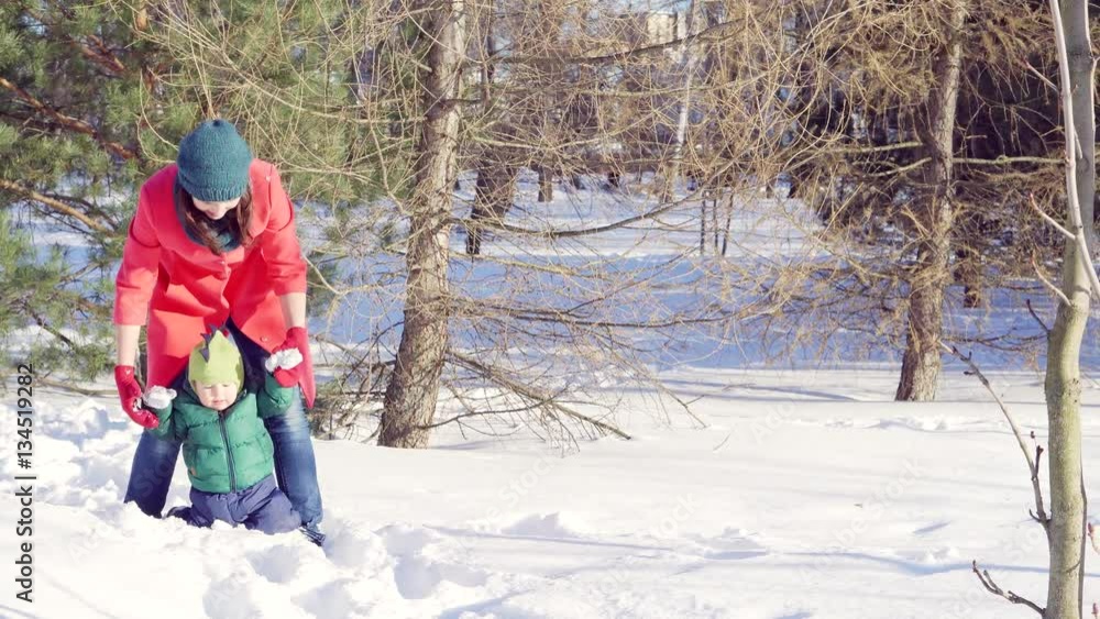 A young mother tries to go in deep snow in the winter in the Park with a young son. A young mother tries to go in deep snow in the winter in the Park with a young son.
