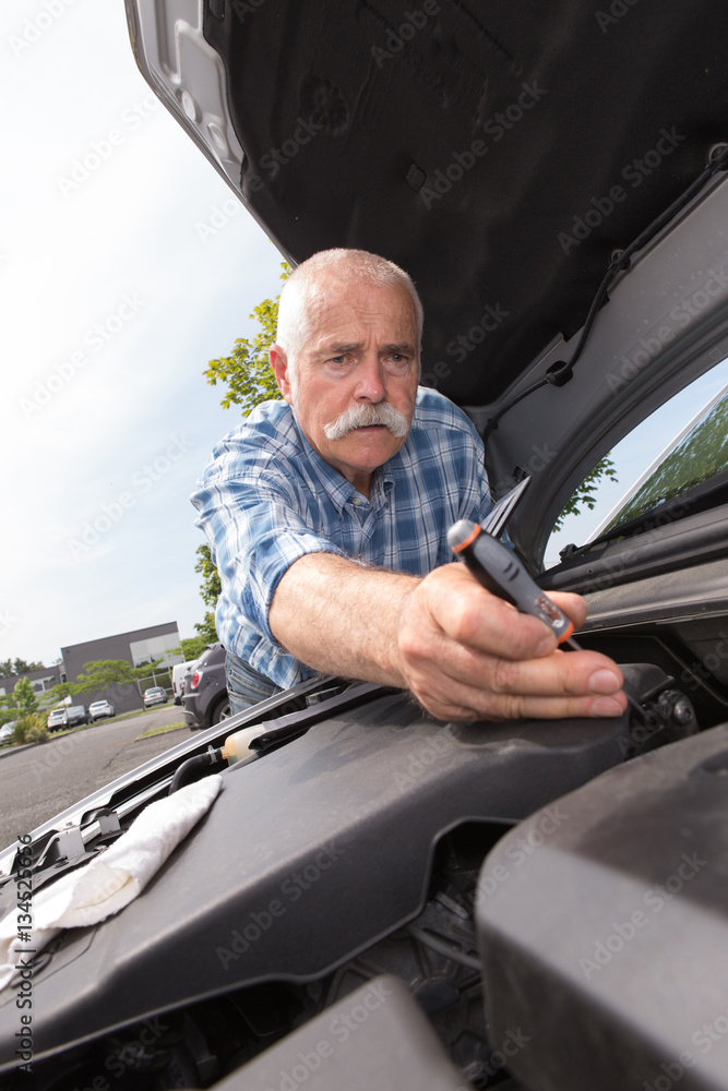 Obraz premium retired man servicing his car engine