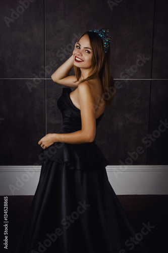 Young beautiful woman in long black dress and diamond crown