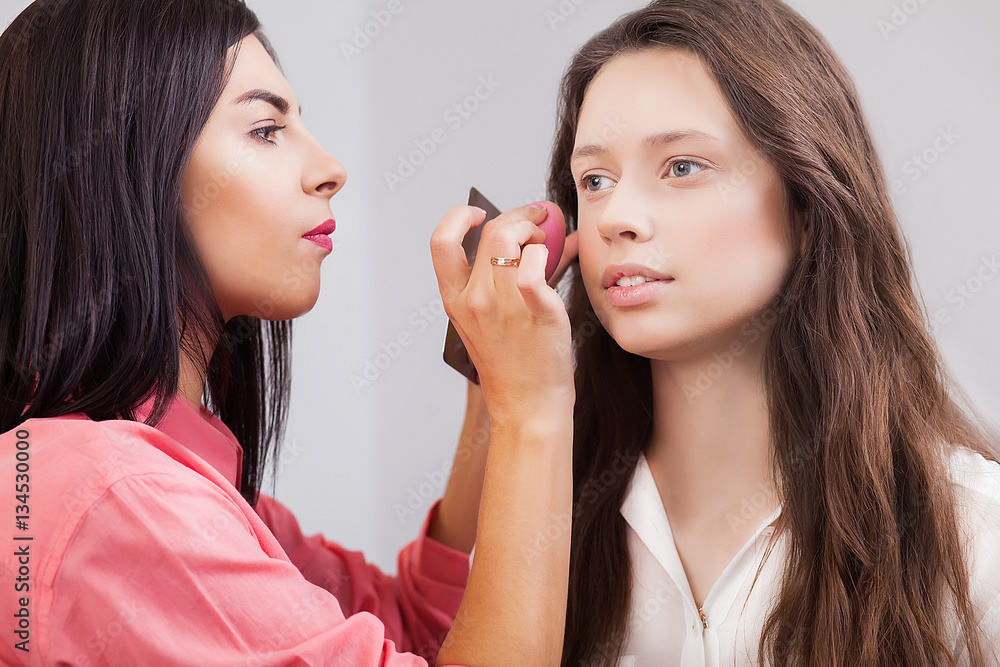 Portrait of beautiful young redheaded woman with esthetician making makeup eye shadow Portrait of beautiful young redheaded woman with esthetician making makeup eye shadow
