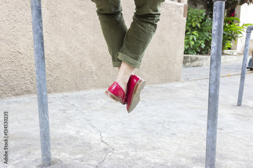Young female with green pants and red shoes against concret