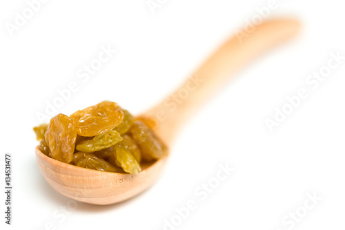 A driend raisin in a wooden spoon isolated over white background photo