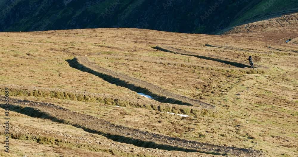 Two hikers making their way up a winding path towards the summit of Sail & Crag Hill in the English Lake District. Two hikers making their way up a winding path towards the summit of Sail & Crag Hill in the English Lake District.