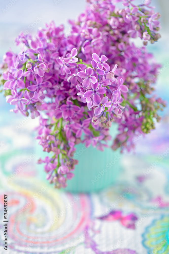 Obraz premium Bouquet of lilacs flowers in a vase on the table.