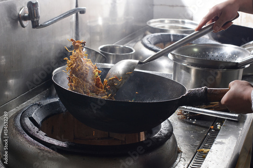 Chef preparing chinese food in vok pan at restaurant