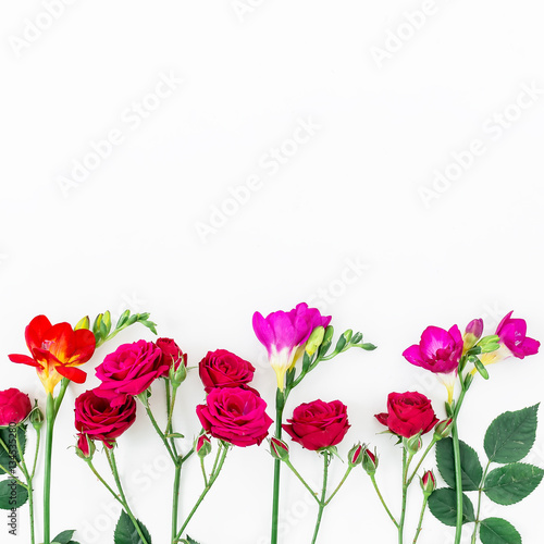 Frame with roses and freesia, branches and leaves isolated on white background. Top view. Flat lay