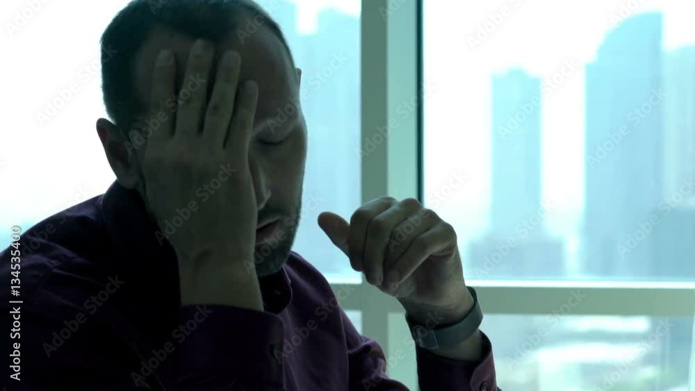 Young businessman having head pain while working with documents in office 
