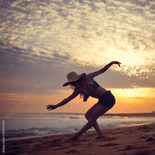 Beach silhouette of the woman dancing during beautiful sun dawn. Natural light and darkness background