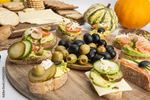 Sandwiches, cheese, crackers and vegetables on wooden boards on