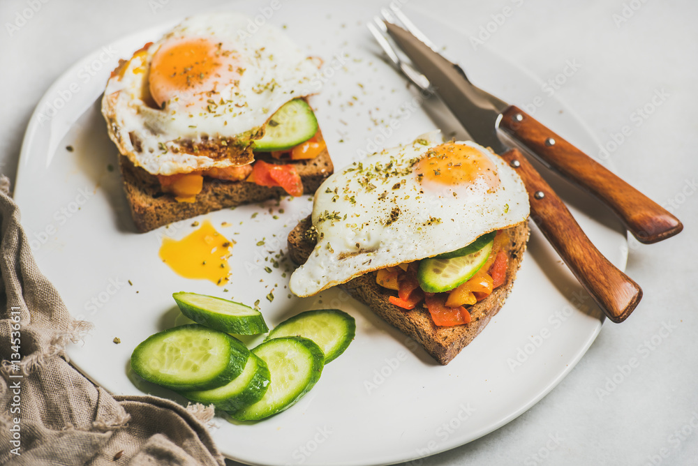 Breakfast toasts with vegetables and fried egg on white plate over grey marble background, selective focus, horizontal composition. Healthy, clean eating, dieting food concept Breakfast toasts with vegetables and fried egg on white plate over grey marble background, selective focus, horizontal composition. Healthy, clean eating, dieting food concept