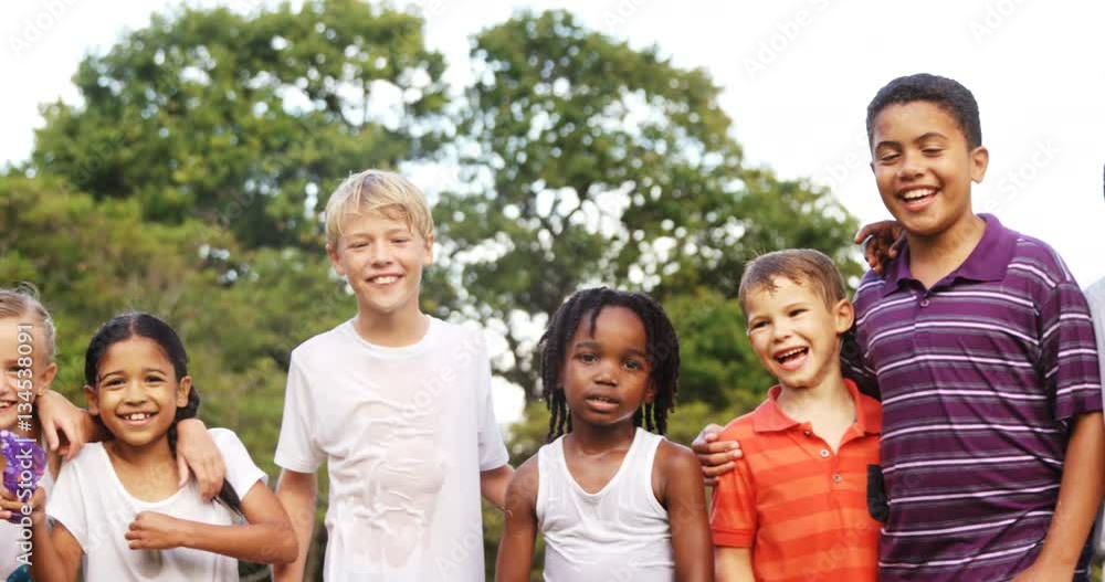 Group of smiling kids standing together with arms around in garden on a sunny day 4k Group of smiling kids standing together with arms around in garden on a sunny day 4k