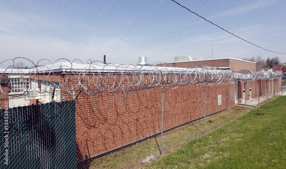 Fototapeta premium Old brick walled county jail topped with razor wire. Horizontal.