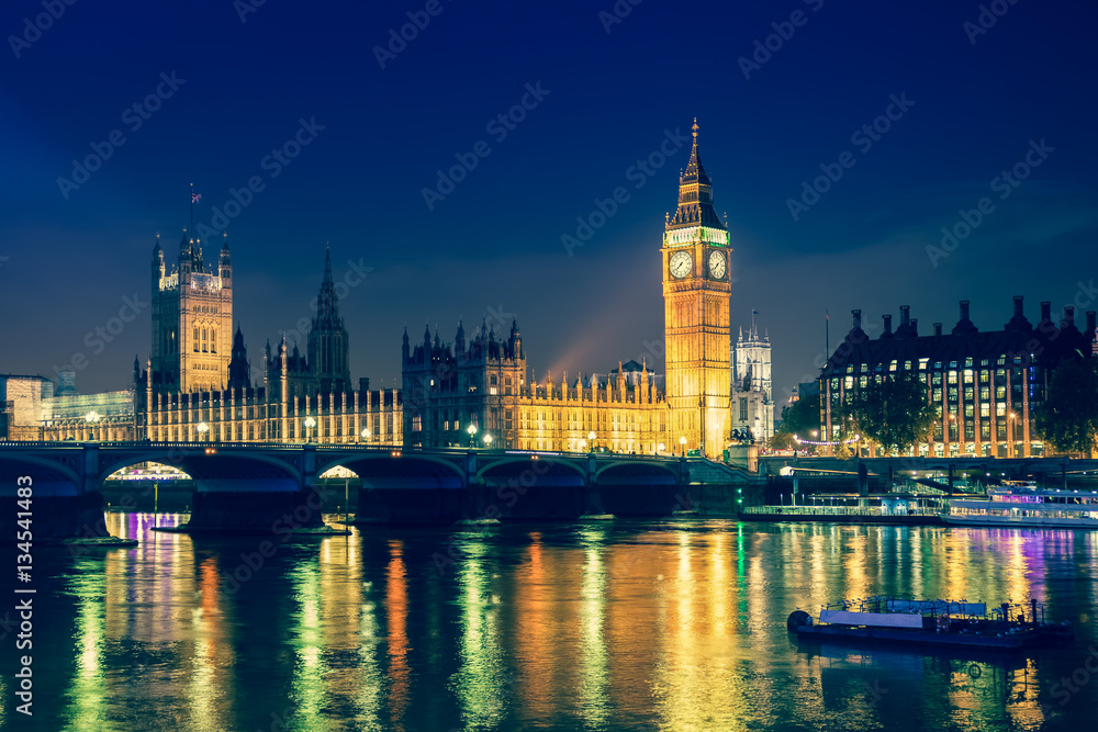 Iconic view Westminster with Big Ben, Houses of Parliament and Thames at Victoria Embankment lit up at night.