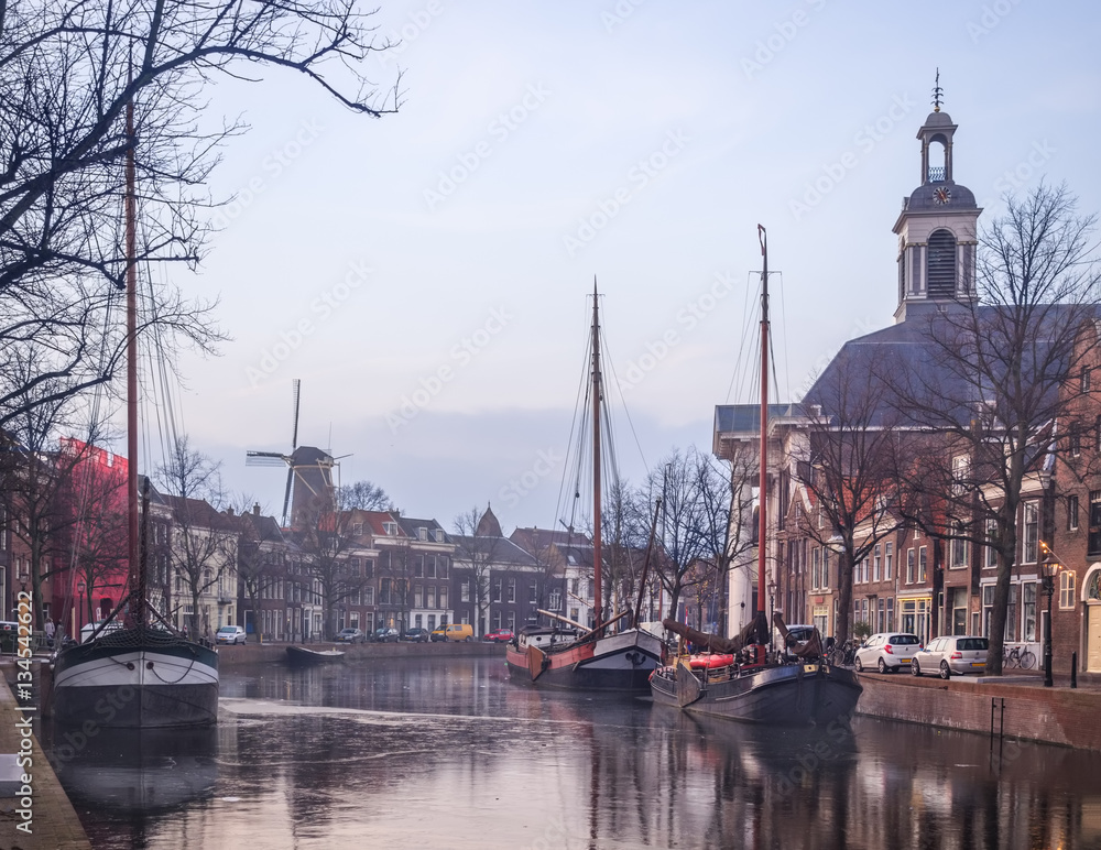 Old Dutch city winter landscape with freezing canal barges and w