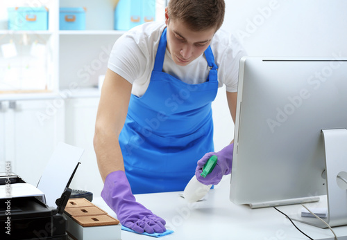 Young man cleaning table in...