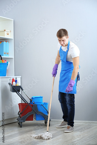 Young man with mop cleaning...