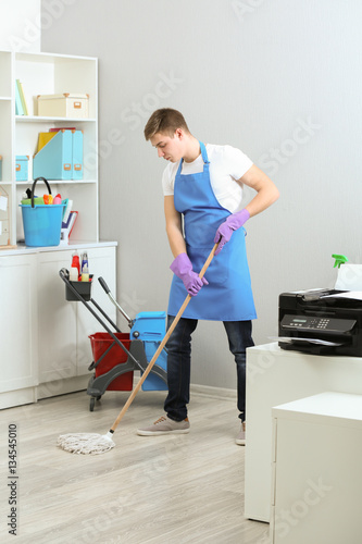 Young man with mop cleaning...