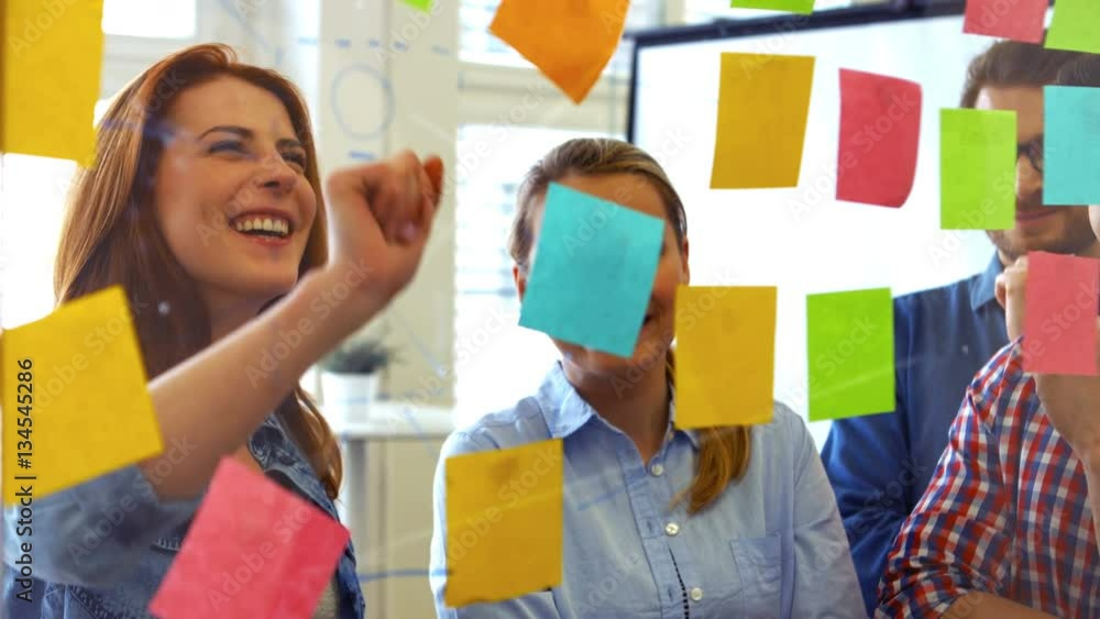 Business executives discussing over sticky notes in office 4k Business executives discussing over sticky notes in office 4k