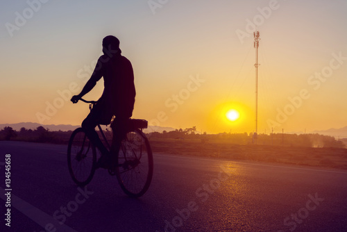 Man Riding Bicycle on Asphalt Road with Sunset