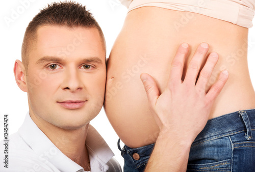 Father listening to mother's pregnant tummy