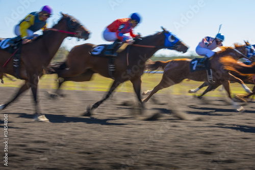Fototapeta Naklejka Na Ścianę i Meble -  Horse Race colorful bright sunlit slow shutter speed motion effect fast moving thoroughbreds