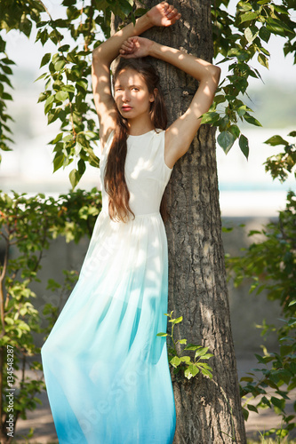 Young sensual woman in long white and blue dress outdoors poses. Professional style. © furmananna
