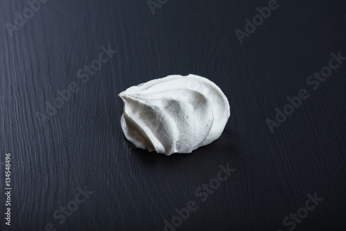 Single fluffy meringue on black table