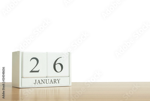 Closeup surface white wooden calendar with black 26 january word on blurred brown wood desk isolated on white background with copy space , selective focus at the calendar
