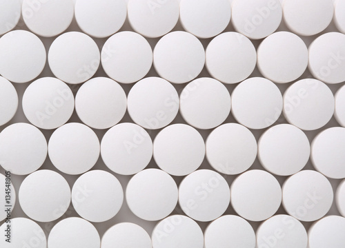 Top view of round white pills closeup sit on a table.