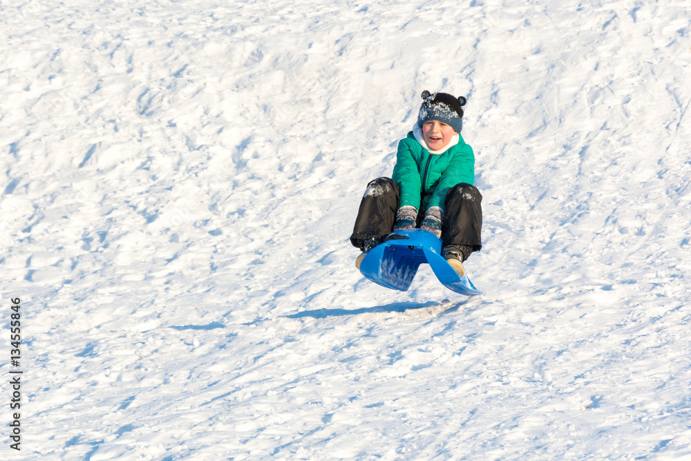 Boy playing in the snow. Sledding on a snowy hill. Winter games. Baby joy of snow. Throwing snowballs.