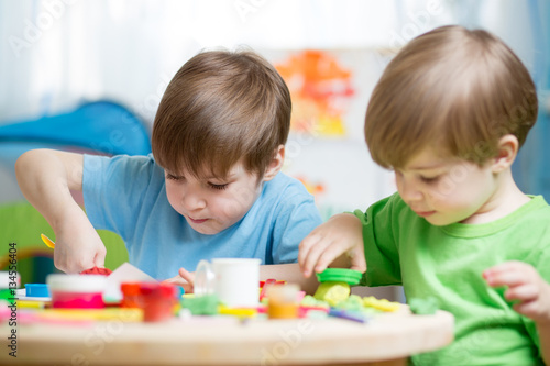 Children creativity. Kids sculpting from clay. Cute little boys mould from plasticine on table in nursery room