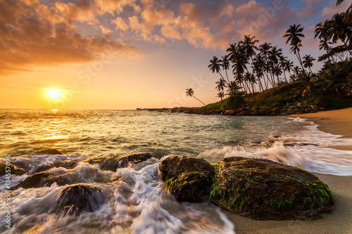 Obraz Zachód słońca na plaży z palmami kokosowymi.