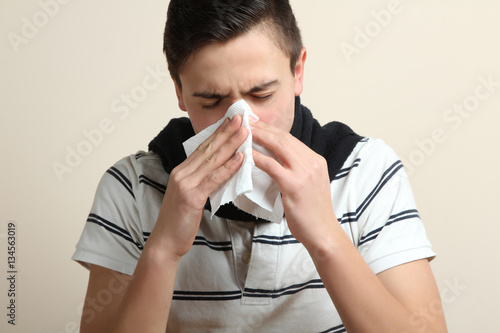 Young man sneezing into a handkerchief. Disease.