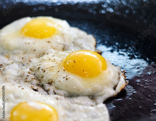 Fried eggs in a frying pan. Process of cooking eggs closeup. Food Background