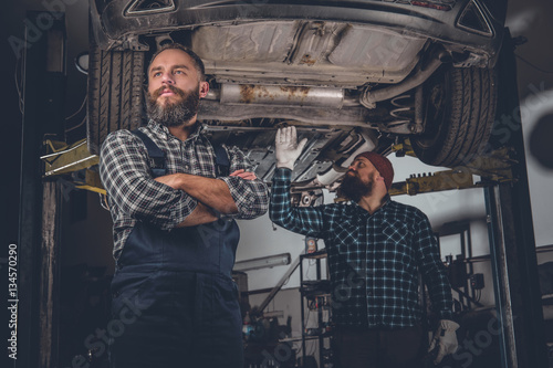 Two bearded mechanics in a garage.
