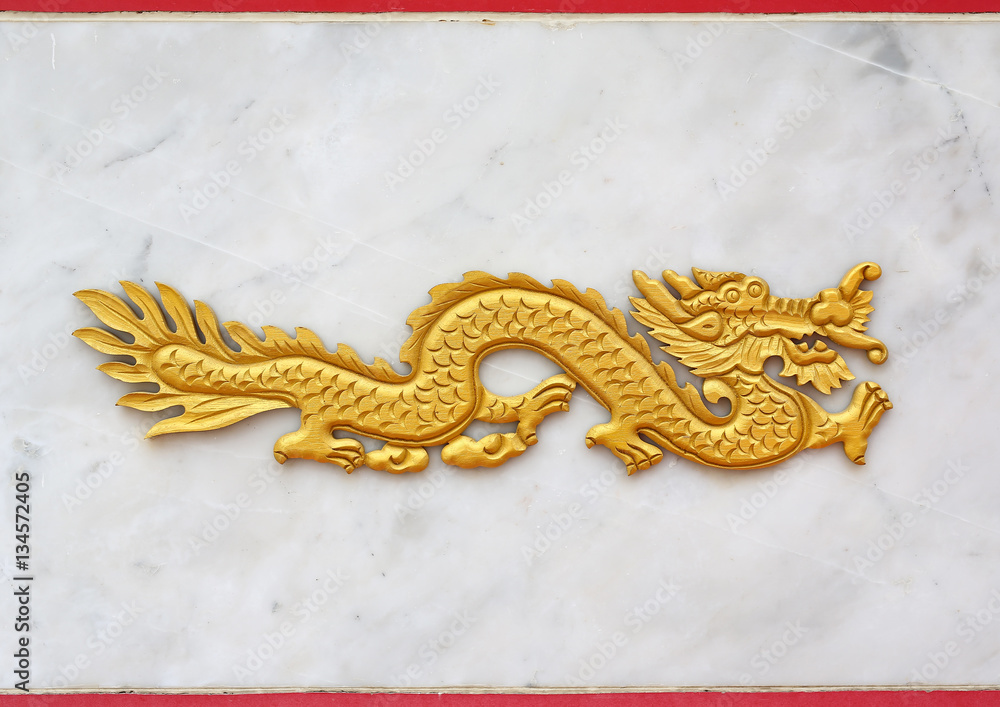 Fototapeta premium Traditional golden chinese dragon wood carved against marble background