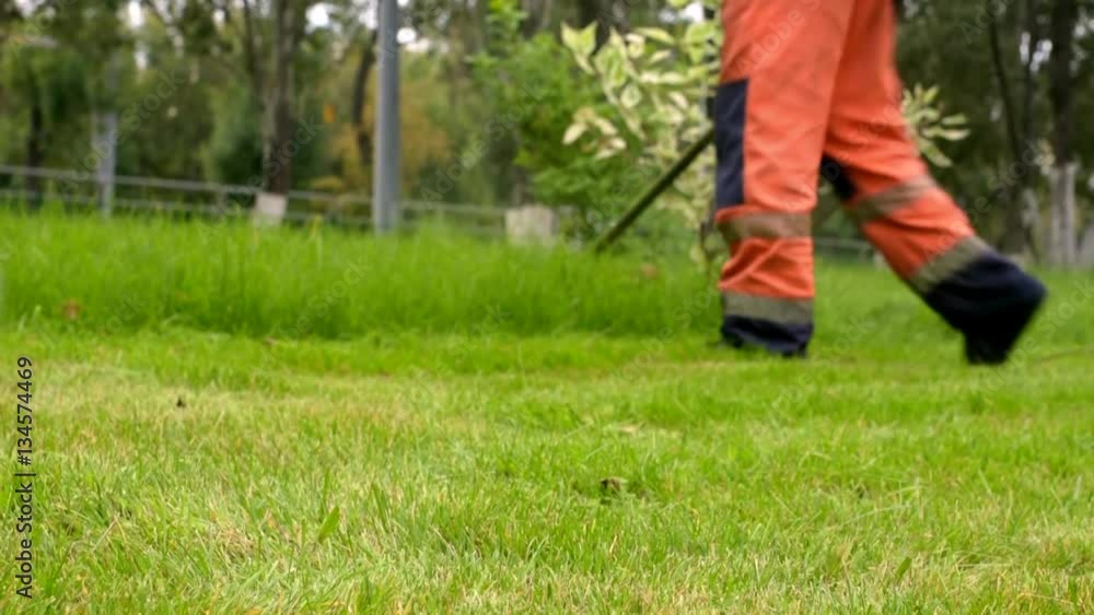City gardening activity. Worker in uniform mowing lawn with trimmer. Urban scene City gardening activity. Worker in uniform mowing lawn with trimmer. Urban scene