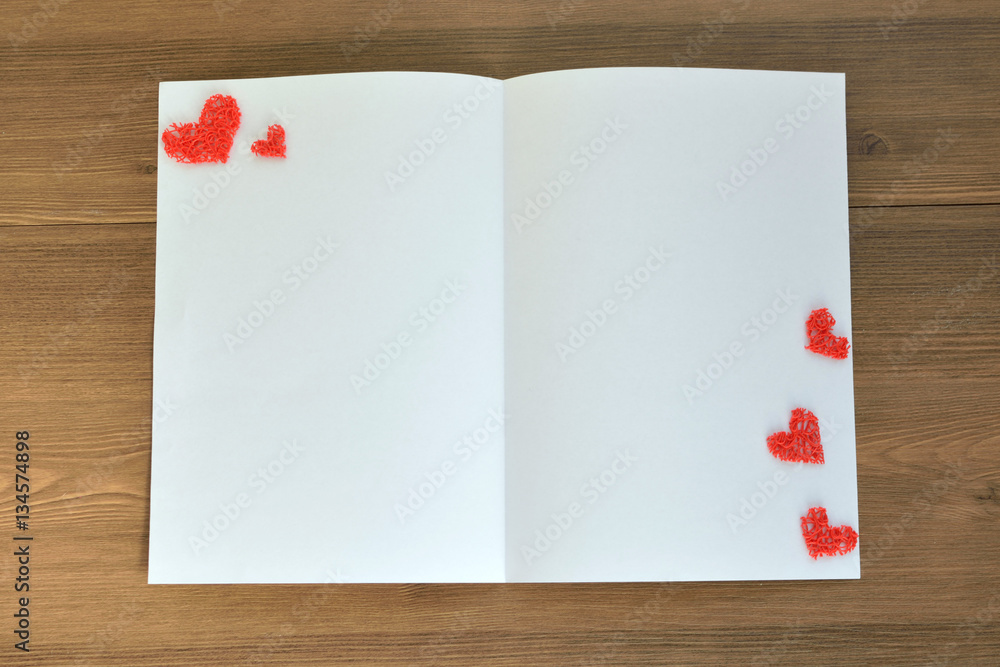 Clean sheet of paper and decorative hearts on wooden background. Valentine's Day. Card for a loved one. Clean sheet of paper and decorative hearts on wooden background. Valentine's Day. Card for a loved one.