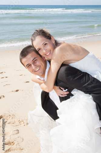 piggyback of wedding bride in marriage day on summer beach © OceanProd