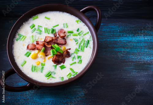 Cheese soup with bacon and corn in ceramic bowl.Dark blue scratched background. Selective focus. Place for text.