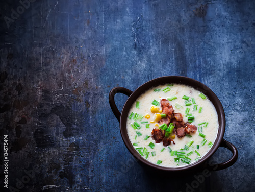 Cheese soup with bacon and corn in ceramic bowl.Dark blue scratched background. Selective focus. Place for text.